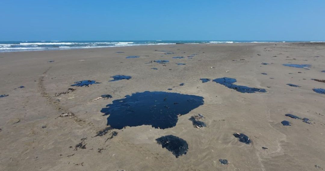 Manchas negras y viscosas de crudo esparcidas sobre la arena de una playa desierta, evidenciando un derrame-de-petróleo.