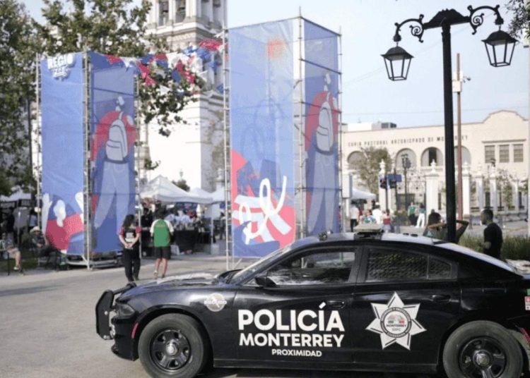 la-logistica-de-resguardo-para-selecciones - VOZ Y OPINION Police car labeled Policía Monterrey in the foreground at an outdoor street festival with blue banners, tents, and people in the background.