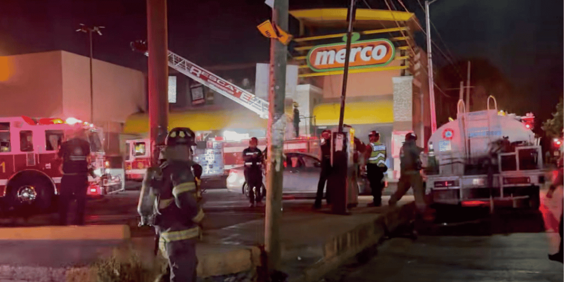 se-incendia-supermercado - VOZ Y OPINION Nighttime emergency scene outside a Merco store with firefighters, police, and a fire truck responding to an incident.