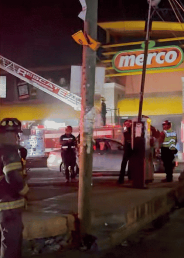 se-incendia-supermercado - VOZ Y OPINION Nighttime emergency scene outside a Merco store with firefighters, police, and a fire truck responding to an incident.